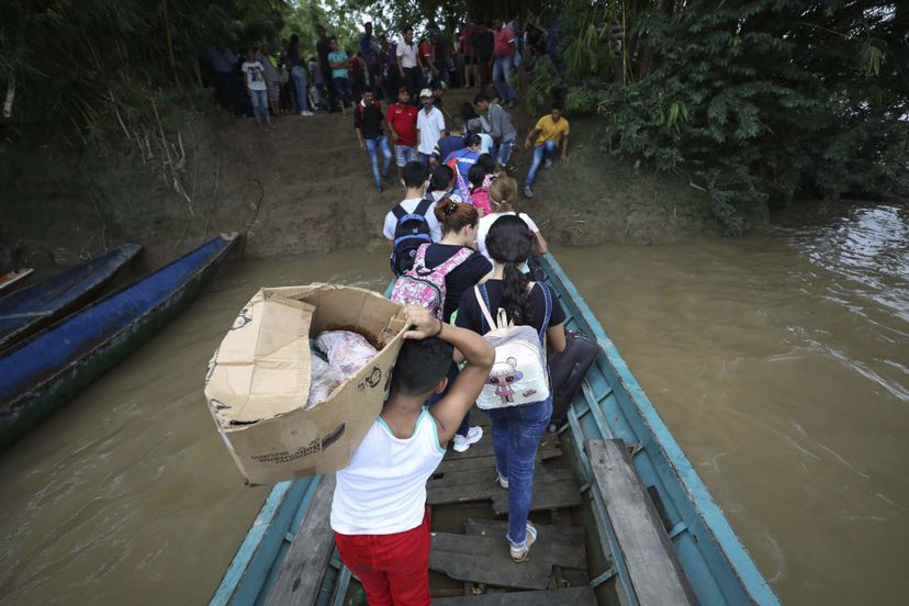Venezolanos que huyen a Colombia por choques armados bajan de un bote en el r&iacute;o Arauca