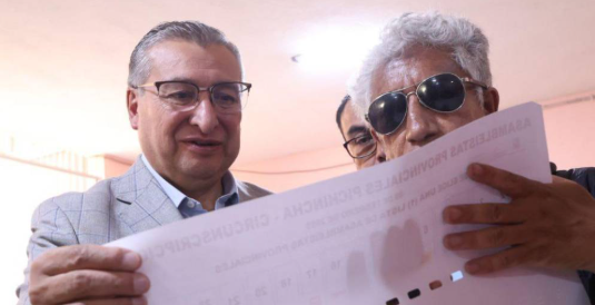 Hombre con discapacidad visual examinando plantilla con braille para la pr&oacute;ximas elecciones en Ecuador