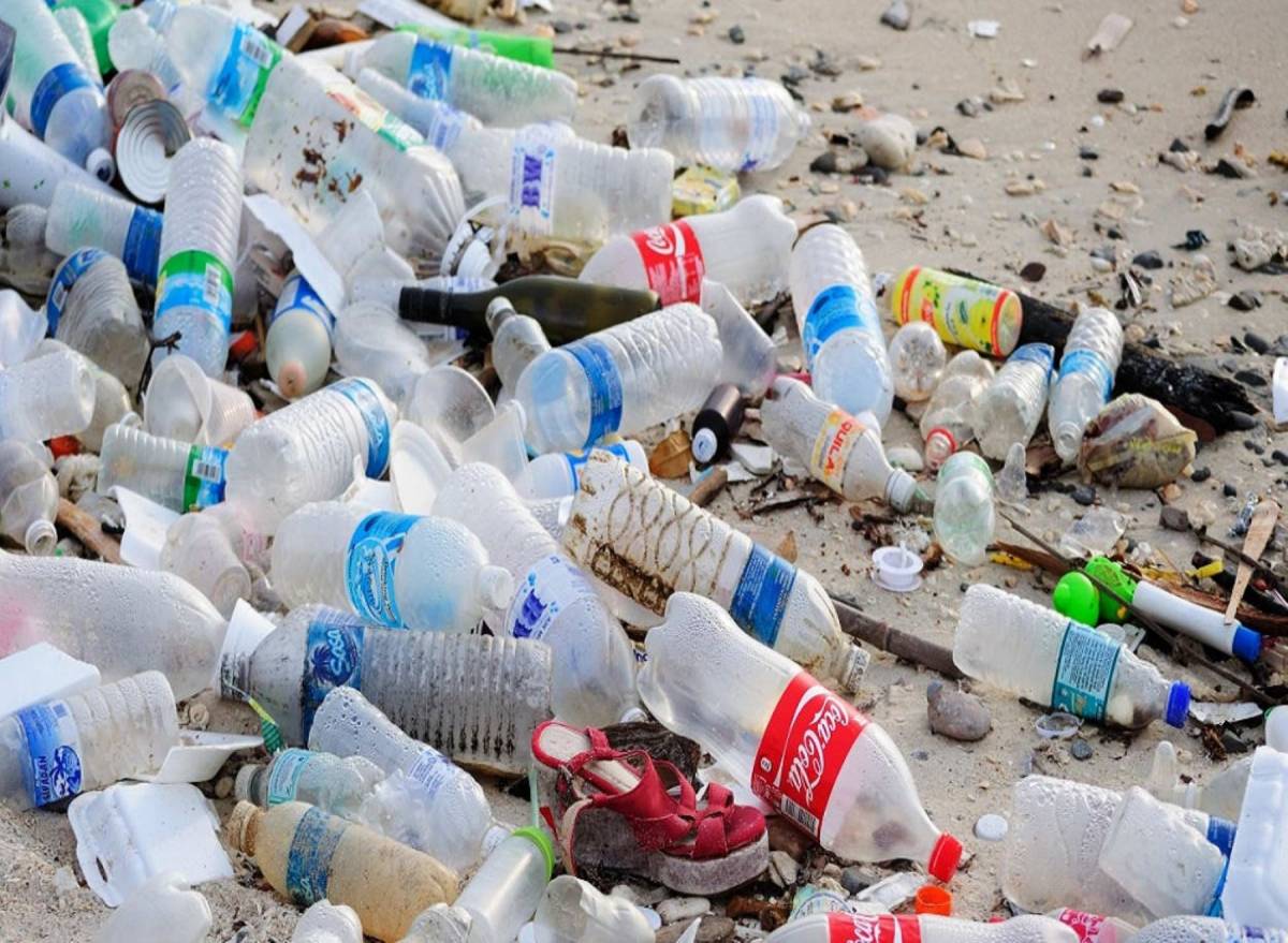 Botellas plásticas acumuladas sobre superficie de arena