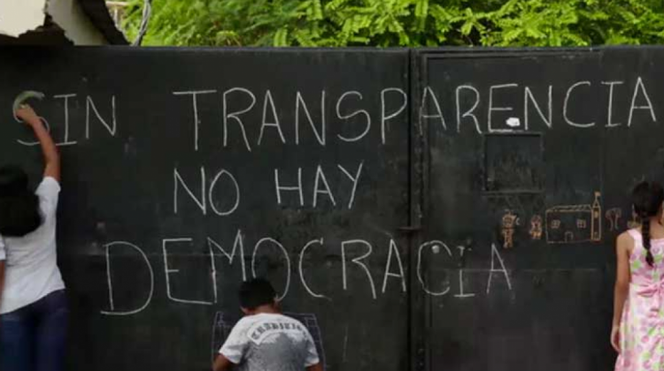Tres personas escribiendo sobre pared "Sin transparencia no hay Democracia"