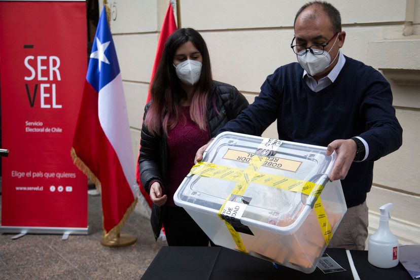 Trabajadores electorales sostienen una caja con votos