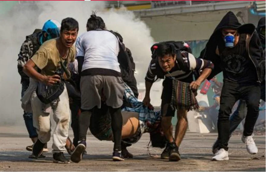 Cinco hombres cargando en conjunto a un herido en una manifestación