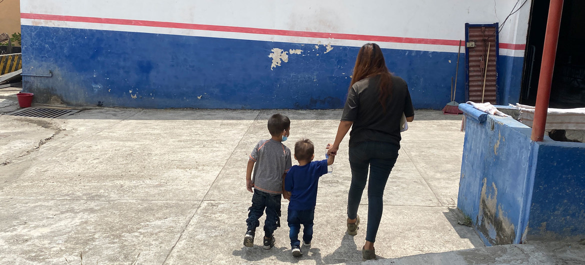 Mujer y dos niños de espaldas en un patio.